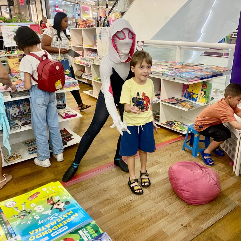 Menino escolhendo livro na estante da loja